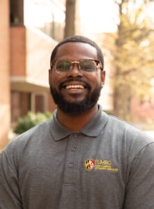 A three quarters informal portrait of a staff member outside in front of a building.