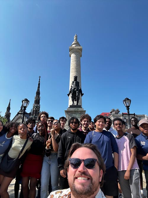 A large group of students posing in front of the Washington monument in Baltimore, Maryland