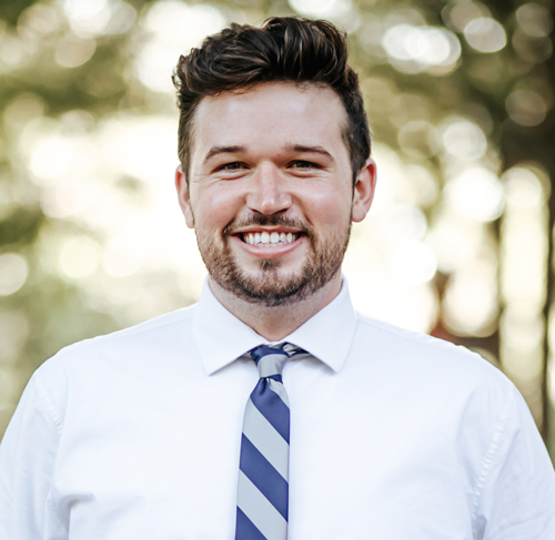 A three-quarter portrait of Gavin standing outside in a garden