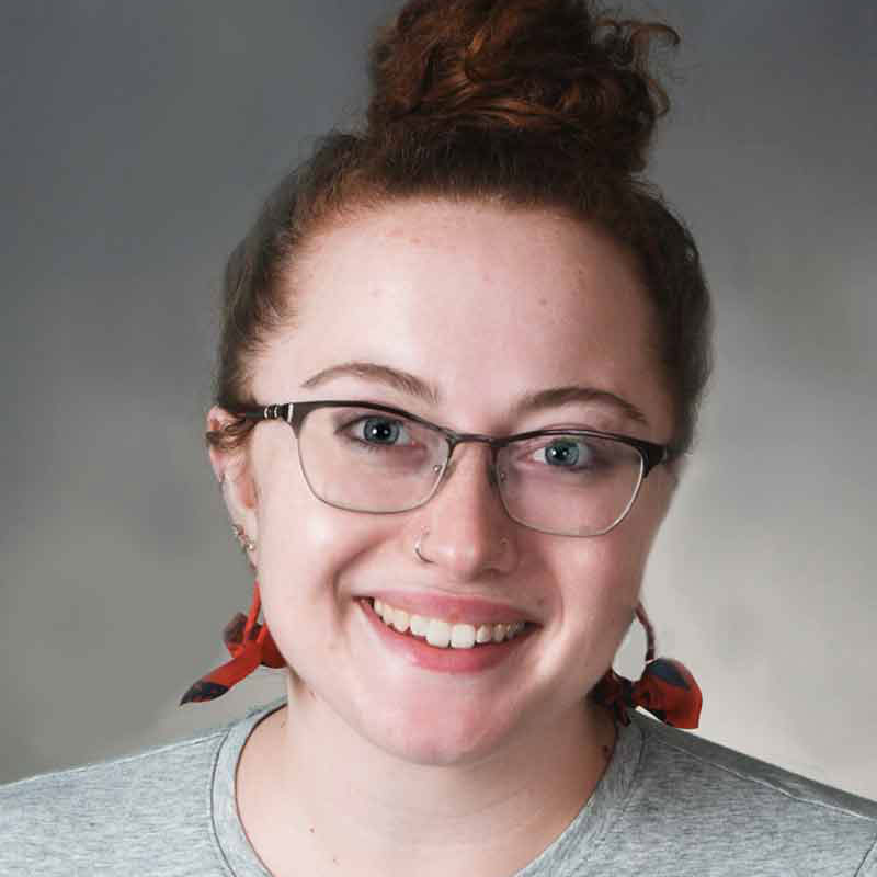 A three-quarter formal portrait of Abby smiling at the camera