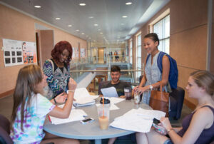 A group of five students around a circular table preparing for an exam